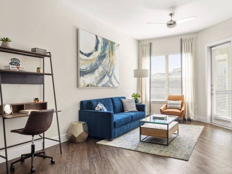 a living room with a blue couch and a desk